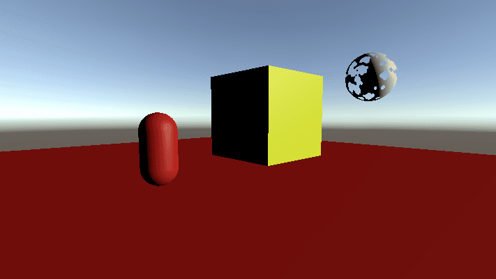 scene showing a red capsule, a yellow cube and a grey sphere with cut outs in it, all are casting shadows, the cube and capsule cast to the floor while the sphere casts to the capsule